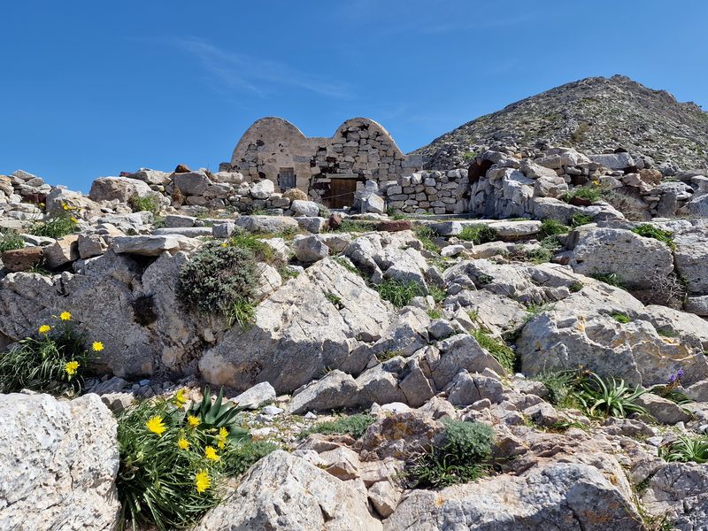 A small domed stone chapel standing among the ruins on the Ancient Thera hillside