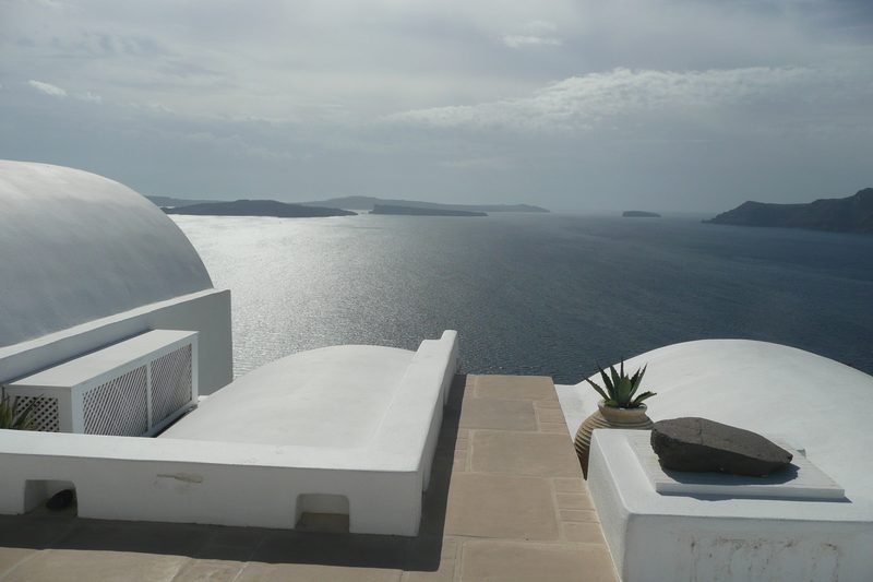 A scenic pedestrian path winds through the cliffs of Santorini, offering views of the Aegean Sea.