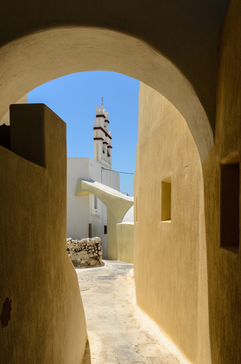 A picturesque street in the old town of Emporeio, Santorini, with traditional whitewashed buildings.