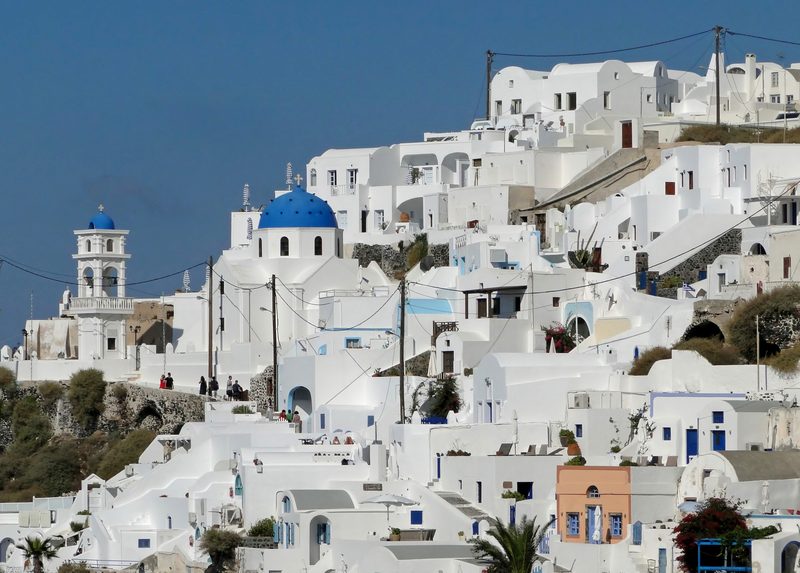 A picturesque village with whitewashed buildings and blue domes in Imerovigli, Santorini.