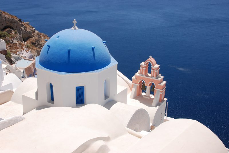 A picturesque blue-domed church stands in the charming village of Oia, Santorini, Greece.