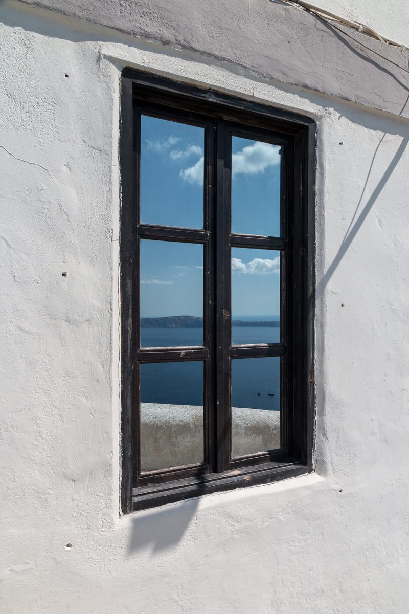 A window with a view of the caldera in Fira, Santorini, Greece.