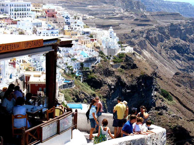 Tourists enjoy a meal with a view of the cliffs in Fira, Santorini.