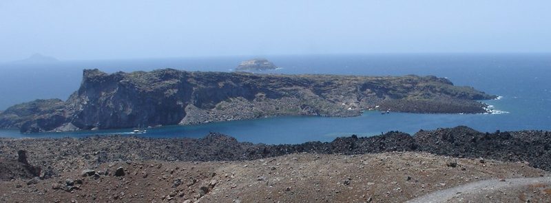 Palea Kameni island in Santorini, Greece, with ships and swimmers near the hot springs.