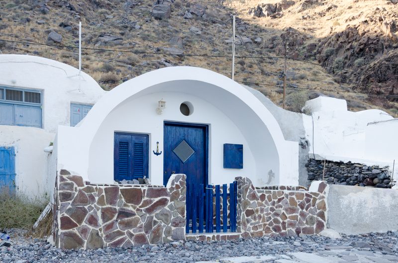 Colorful fishing huts line the shore of Korfos harbour in Thirasia, Santorini.