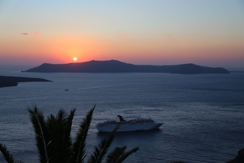 A group of tourists enjoying a sunset cruise on a boat in Santorini, Greece.
