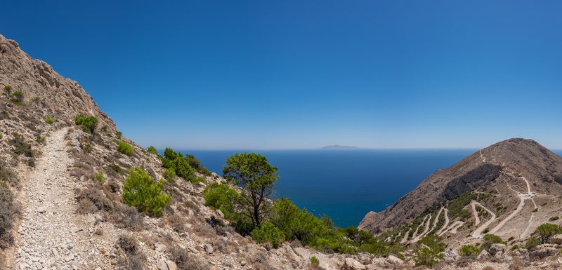 A winding road to Ancient Thera with Anafi Island visible in the distance, Santorini, Greece.