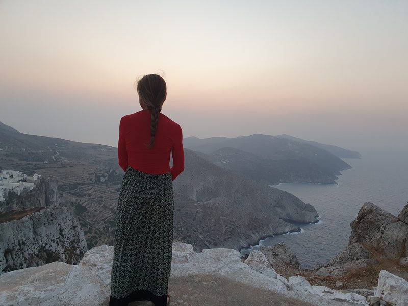 Looking out from the clifftop path above Folegandros Chora toward the terraced coastline at dusk