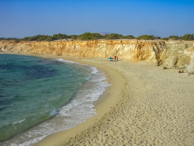 A serene beach with clear waters and rocky formations on the Greek island of Naxos.