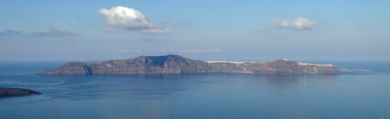 A serene view of Therasia Island in the Santorini group, showcasing its rugged cliffs and tranquil waters.