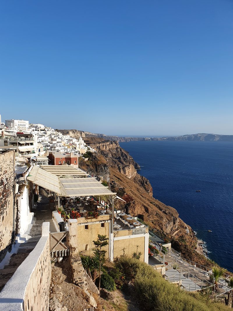 The cliffside walking path along the caldera rim at Fira, lined with cafe terraces and sea views
