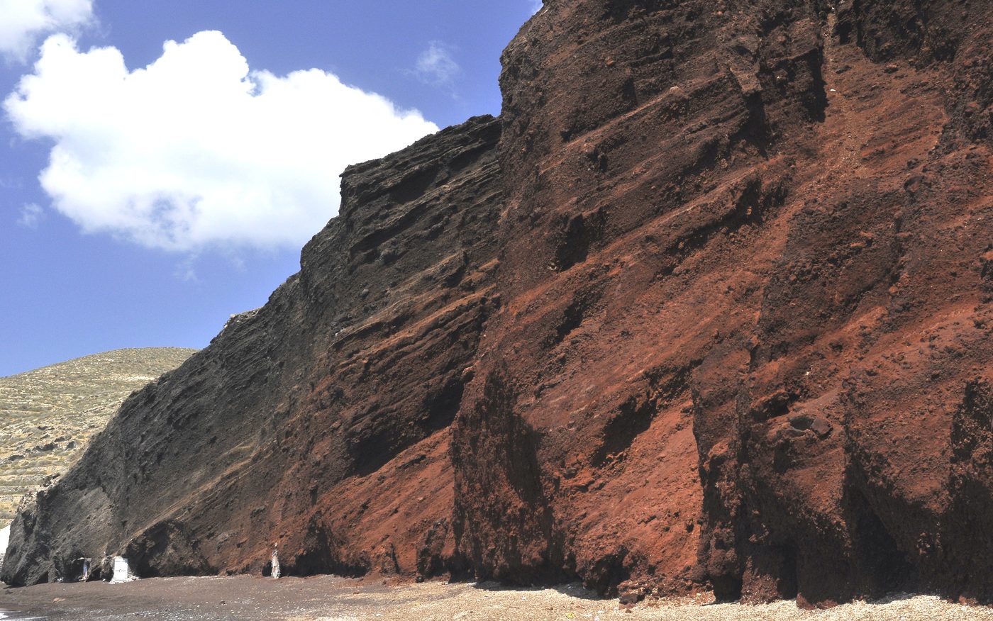 The dramatic red volcanic cliffs and dark sand of Red Beach near Akrotiri, Santorini