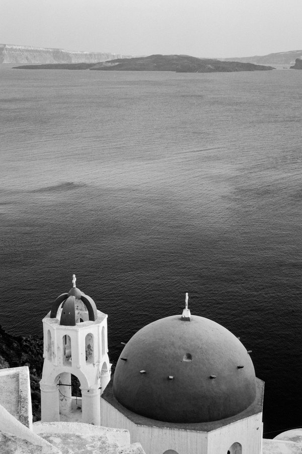 A blue-domed church above the Santorini caldera in Oia, overlooking the Aegean Sea