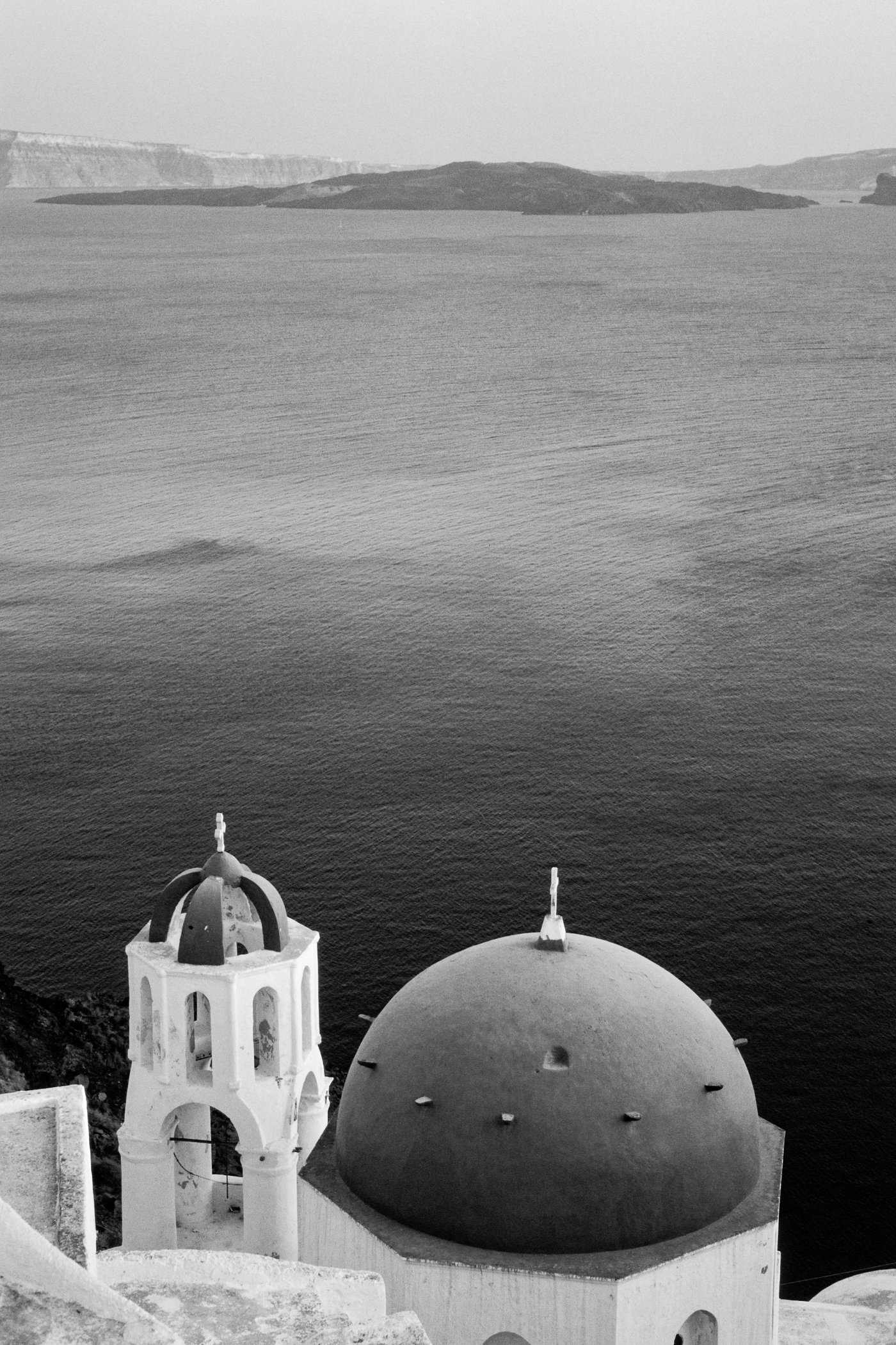 A blue-domed church above the Santorini caldera in Oia, overlooking the Aegean Sea