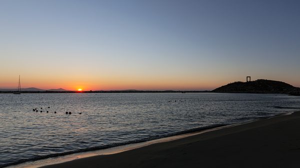 Sunset over Naxos Chora with the Portara temple gate silhouetted against the sky