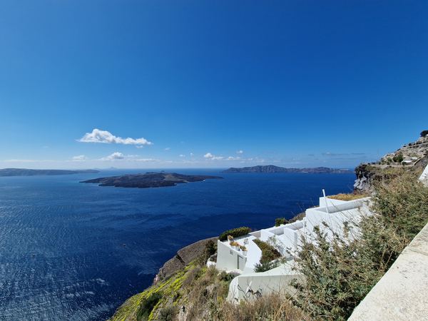 View over the Santorini caldera from the Fira cliff path, white buildings below and the volcano islands offshore